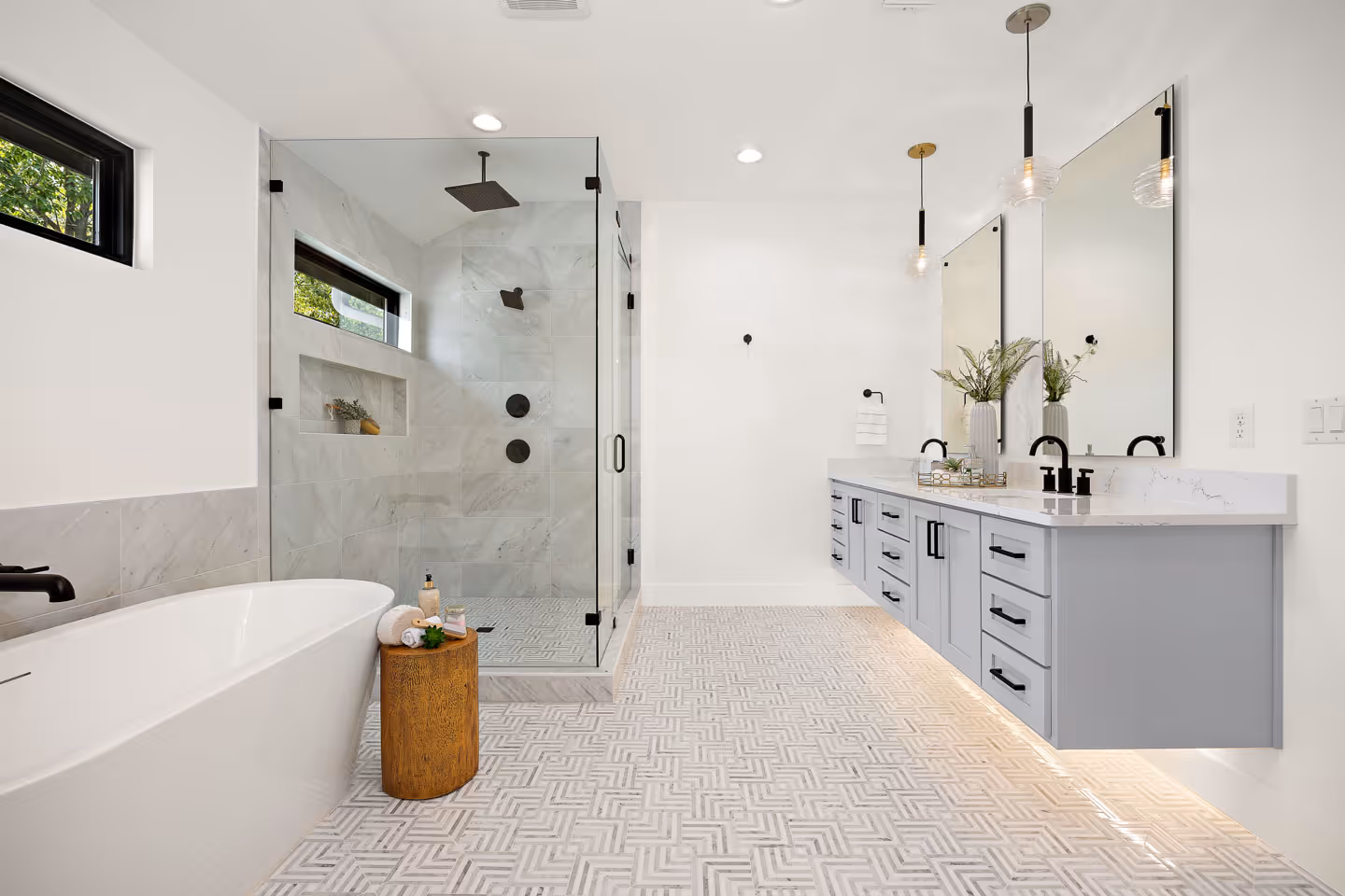 Modern bathroom with a freestanding bathtub, walk-in glass shower, floating vanity with dual sinks, and patterned floor tiles.