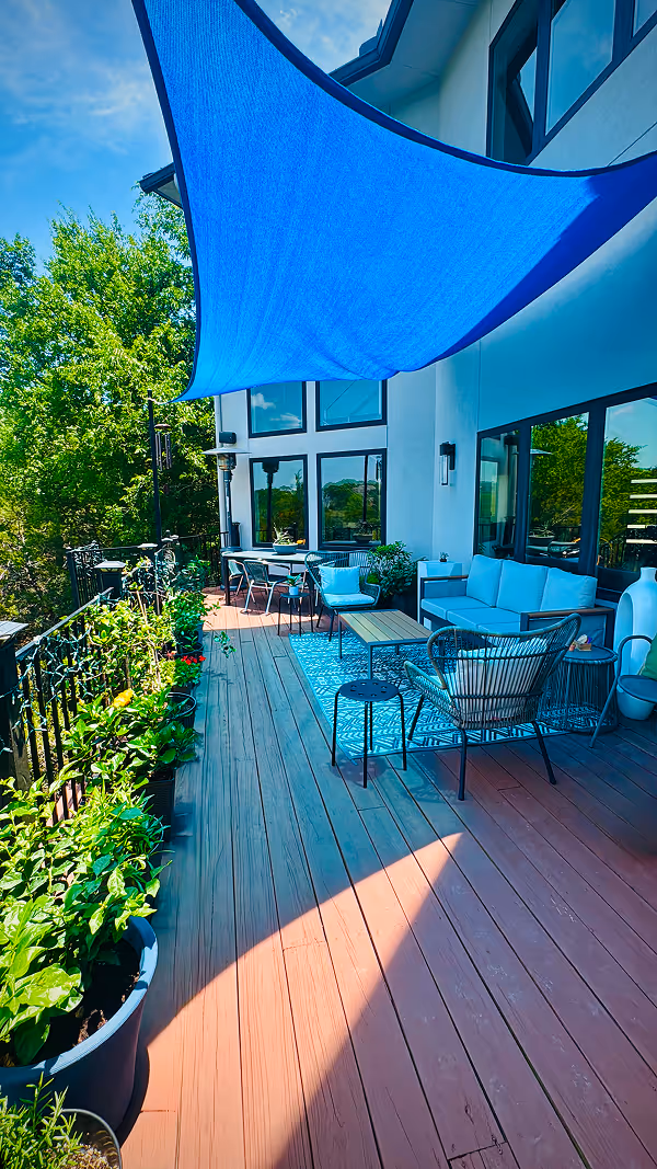 Modern open living space with wooden floors, a wall-mounted TV above a sleek fireplace, and a kitchen island with bar stools and pendant lights.
