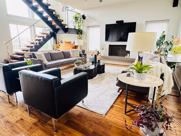 Modern kitchen with gray cabinets, marble countertops, island with bar stools, built-in ovens, and gray tile flooring.